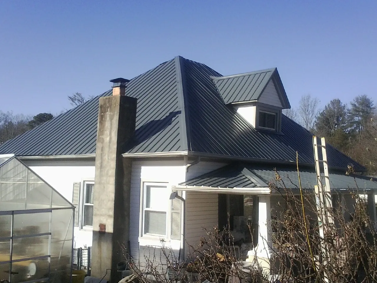 Dark blue standing seam metal roof on a white farmhouse with dormer — Slate & Tile Roof Repair by Roofing Brothers in Colchester