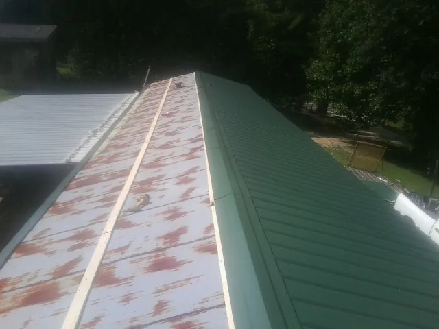 Old rusted panels beside newly installed green metal roofing — Wind Damage Roof Repair by Roofing Brothers in Colchester